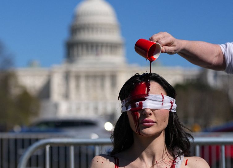 Demonstrator Sam Scarcello, in costume, has fake blood poured on her head during a 